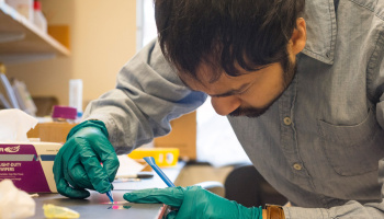 Photo of the top of Devashish Gokhale's head as he bends over a workbench 