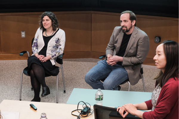 Professors Mary Gehring and Matt Shoulders sit at front of a lecture hall, listening to a question being asked by someone off camera, with Longzhen Han standing on the side also listening