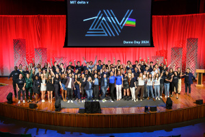 About 70 people raise their hands in celebration on a stage