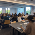 Several people sitting at tables in the conference room at the workshop.